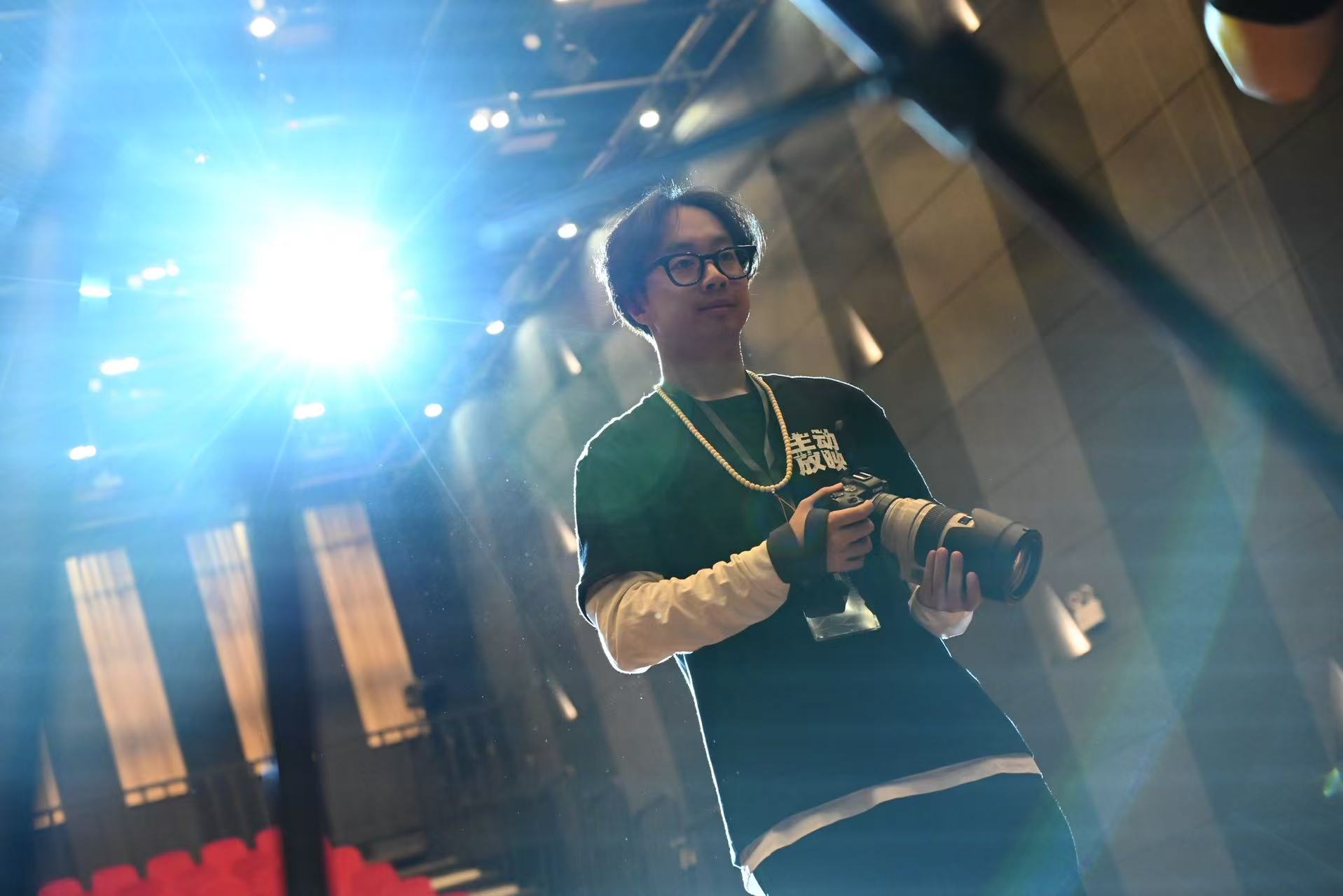 李浩铭在剧场灯光下手持相机的工作照